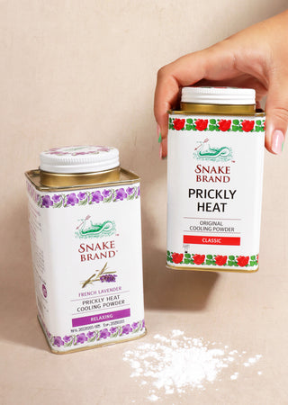 Photo shows two cans of Snake Brand powder, to the left there is an lavender tin and to the right is the classic tin. There is some powder below.