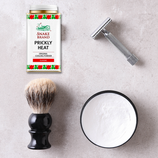 Snake brand cooling powder next to a beard shaving brush, a razor and cream